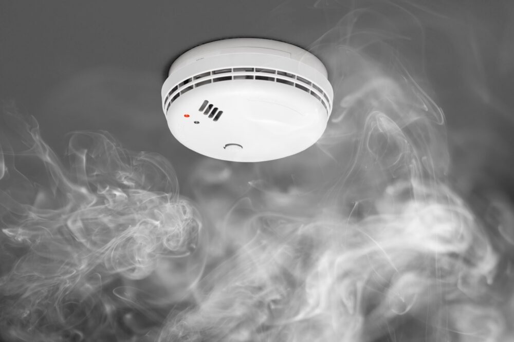 Fire alarm on a ceiling with wisps of smoke around it